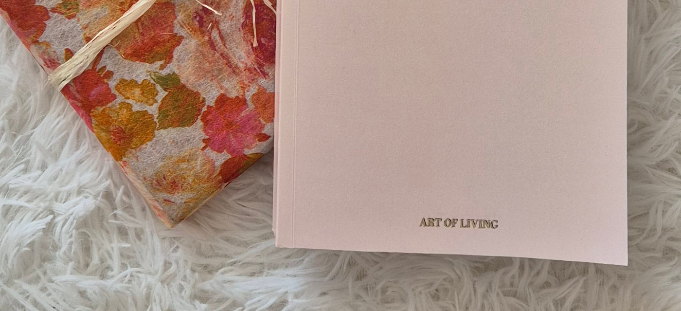 Detalle de la agenda impresa: la tapa en tono nude con Art of Living estampado en oro, junto a un paquete envuelto en papel de flores